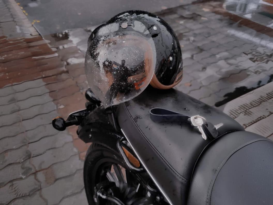 A motorcycle helmet resting on the seat of Harsh's motorcycle